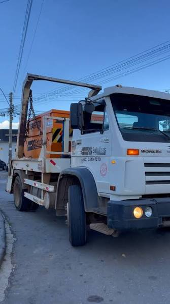 Caminhão poliguindaste entregando caçamba